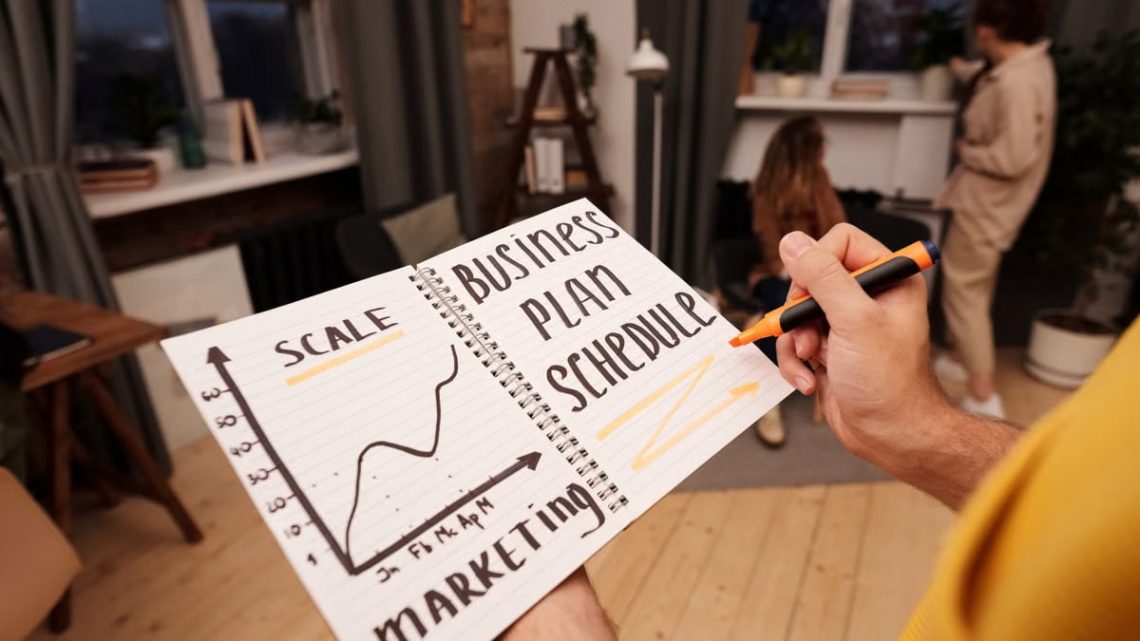 Person holding a notebook with planning details and graph for business strategy indoors.
