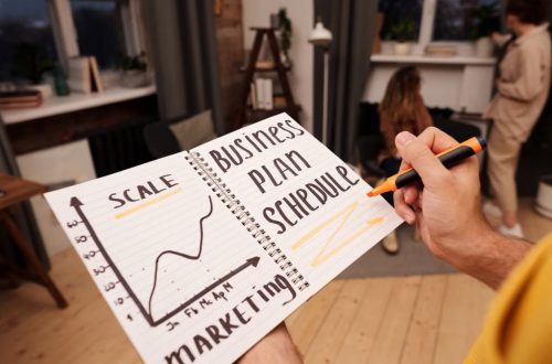 Person holding a notebook with planning details and graph for business strategy indoors.